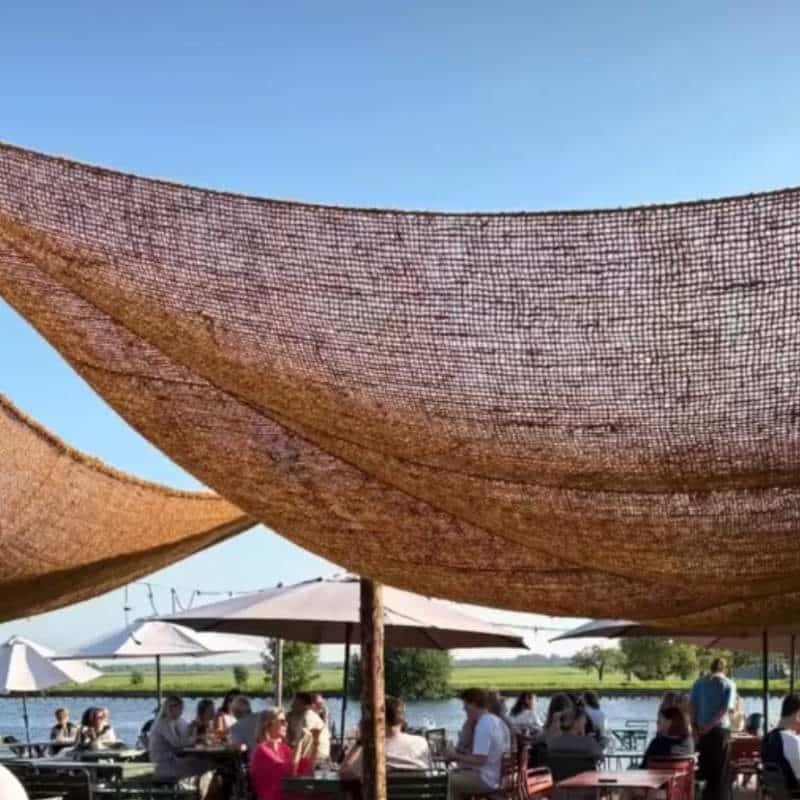 Rechthoekige kokos schaduwdoeken boven een terras aan het water
