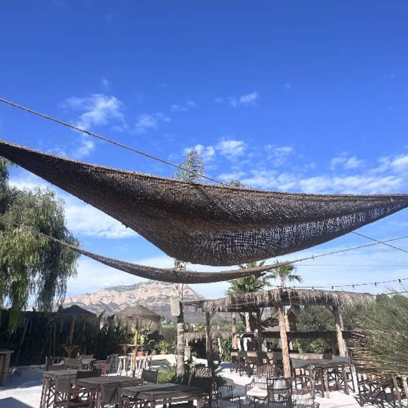Driehoekig kokos schaduwdoek boven een terras met bergzicht