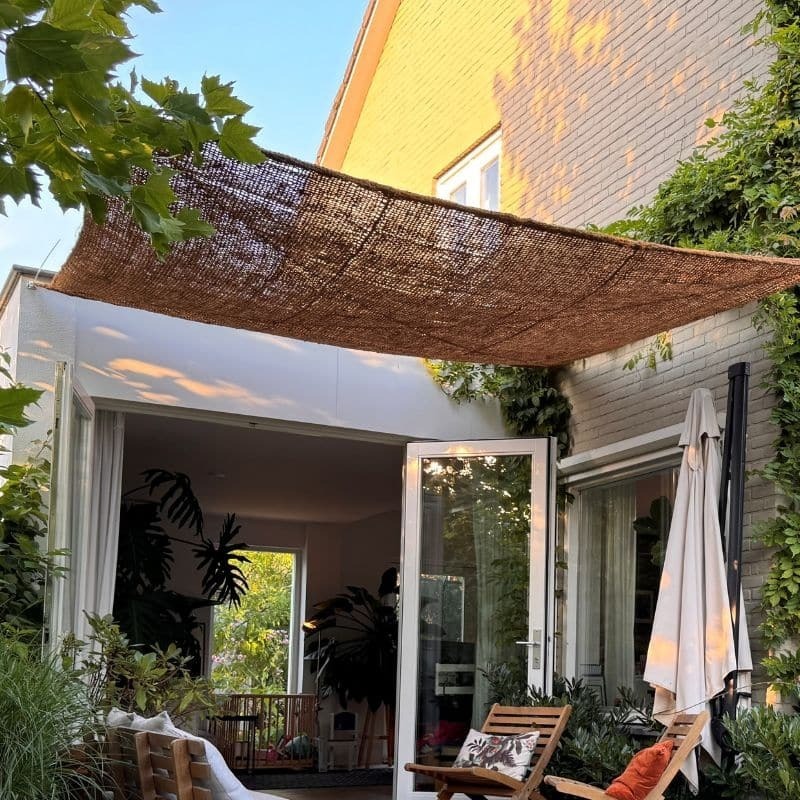 Kokos schaduwdoek gespannen boven een stadstuin bij een woonhuis